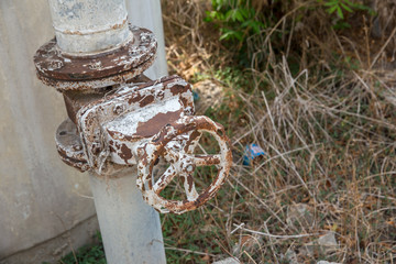 A metal pipeline valve, old weathered gas crane and pipe .Old valves have rust, Circular handle,...