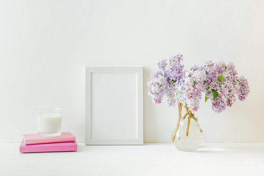 Mockup with a white frame and branches of lilac in a vase on a light background