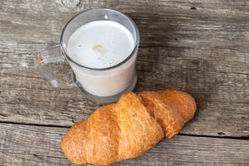French breakfast with croissant and cappuccino over wooden background