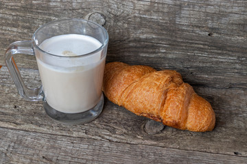 French breakfast with croissant and cappuccino over wooden background