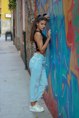 Trendy beautiful long haired young model posing on graffiti background