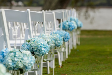 Bouquets of hydrangeas hanging from chairs for outdoor wedding.