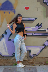 Trendy beautiful long haired young model posing on graffiti background