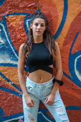 Trendy beautiful long haired young model posing on graffiti background