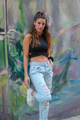 Trendy beautiful long haired young model posing on graffiti background