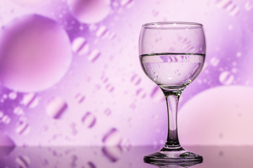 transparent glass with water and oily drops on background 