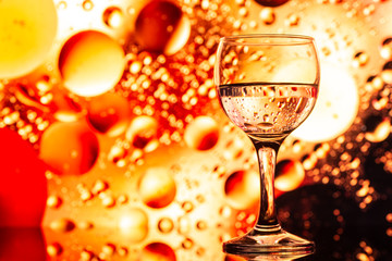ransparent glasses with water and oily drops on colorful background 