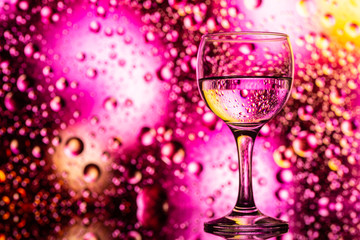 transparent glasses with water and oily drops on colorful background 