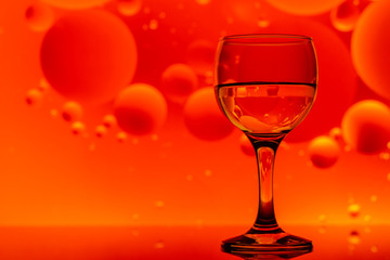 transparent glasses with water and oily drops on colorful background 