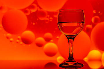 transparent glass with water and oily drops on background 