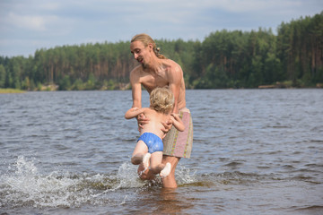 father teaching his little son to swim, they are happy. summer time. happy family on the beach.