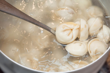 Fototapeta na wymiar Stirring ravioli boiling in an aluminum saucepan as cooking semi-finished products