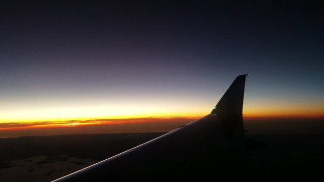 View from passenger seat of an airplane in the mid air on a calm stable airflow during sunset