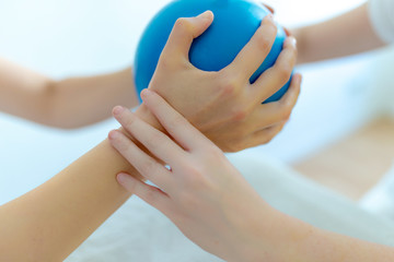 Physiotherapeutin macht Übungen mit Pilates Ball