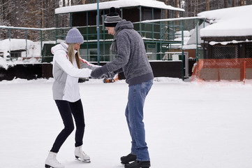 Young couple skating at a public ice skating rink outdoors in the city