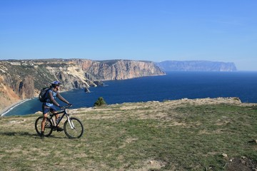 Cyclist admires the view on the edge of the cliff on the Black sea, Crimea, Russia.