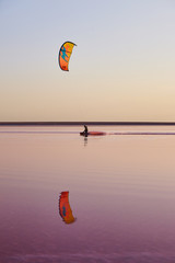 Kitesurfing on pink color lake with reflection