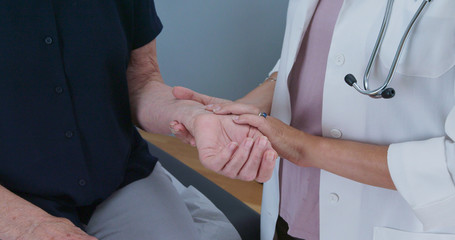Close up of female doctor taking senior womans radial pulse. Older patient making regular visit to...