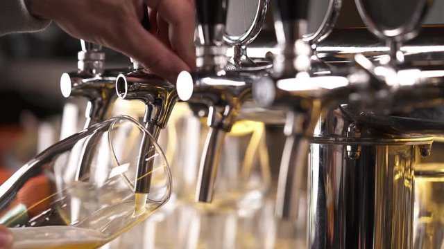 Bartender pouring draft beer in the bar. Close-up demonstration video. Beer is poured into a glass.