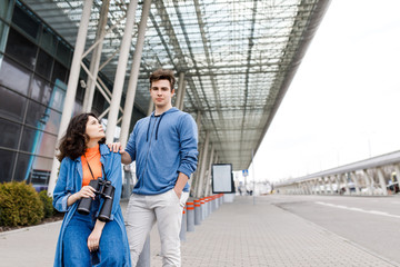 Young pretty couple - a boy and a girl walking around the city with a binocular in his hands. Young people travel.