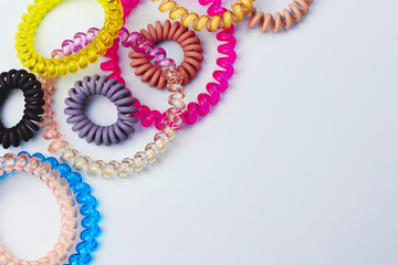 Plastic spiral scrunchies hair band for women hairdressing hairstyle on blue background with free copy space for text flat lay