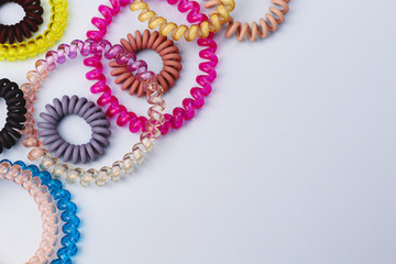 Plastic spiral scrunchies hair band for women hairdressing hairstyle on blue background with free copy space for text flat lay