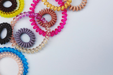 Plastic spiral scrunchies hair band for women hairdressing hairstyle on blue background with free copy space for text flat lay