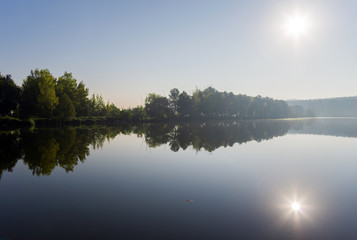 Bright sun reflected in the water of the lake. Calm on the lake.