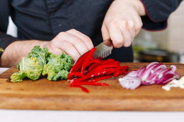Chef cut pepper and vegetables. Wooden. Kitchen. Healthy food. Raw.