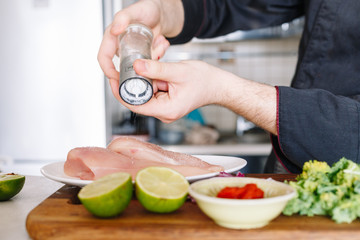 Chef salting raw chicken fillet. Making. Kitchen. Lime. Cook hands. Cuisine.