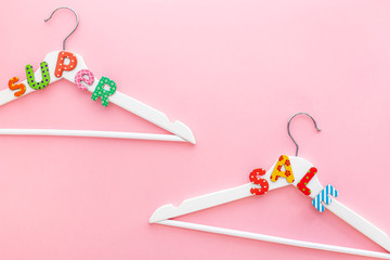 White hangers with sale text on pink background