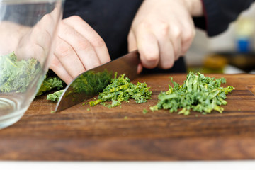 Cook cuts arugula. Makin. Chef. Homemade. Wooden.