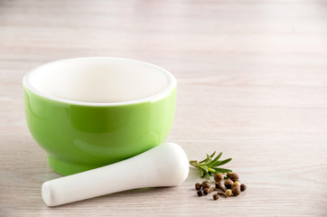 Green ceramic mortar and pestle with spilled mixture of pepper beans at the vintage background