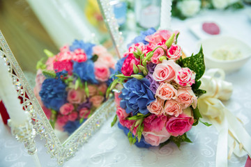 The appearance of the wedding rose is in the mirror . Selective focus . Wedding bouquet of Multicolored on a wooden table. Copy space.