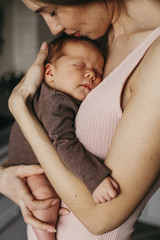 Young mother, holding tenderly her newborn baby girl, close portrait - obrazy, fototapety, plakaty