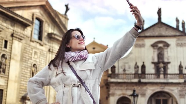 Happy tourist woman smiling taking selfie using smartphone at historic castle background