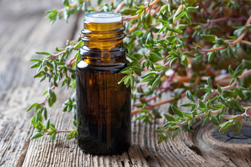 A bottle of thyme essential oil with fresh thyme