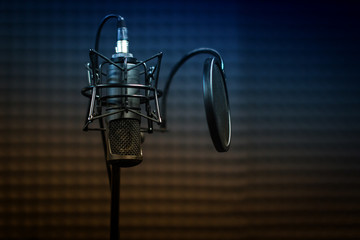 Microphone close - up on the background of a professional recording Studio. Workplace singers and musicians. Microphone stand for recording vocals, speakers and sound of musical instruments.