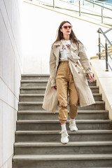 Portrait shooting of a stylish girl. Beige shades. Trends of spring and summer 2019. Pants of cork.Trench cloak, a wide jacket.