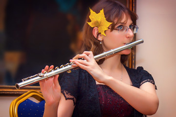 The girl plays a large silver transverse flute. A woman in purple dresses blows a flute at a concert. In the hands of the musician metal musical instrument © Андрей Журавлев