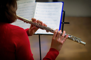 The girl is holding a large concert flute (in hands close-up). Professional musician at the rehearsal. A woman plays the transverse flute. © Андрей Журавлев
