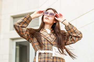 Portrait shooting of a stylish girl. Beige shades. Trends of spring and summer 2019. Wide jacket and belt leather bag. White sneakers and bike shorts