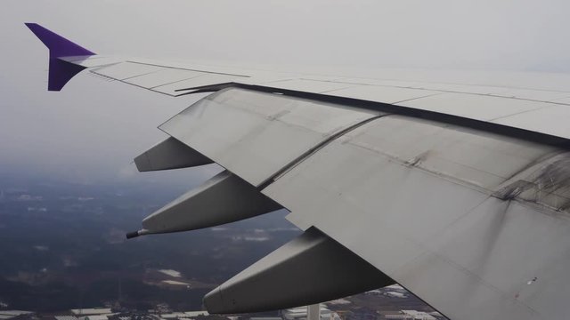 Wing of airplane flying in the sky while landing at the airport