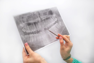 A dentist examines orthopantomogram in her hands against the background of the dentist tool