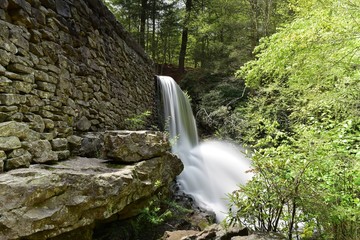 Side view of a stone dam with a flowing waterfall