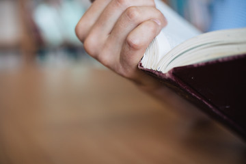 Male hand holds the opened book. View of the book back close-up.