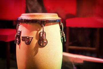 Traditional ethnic Cuban Djembe drum on red background. Percussion instruments made of wood covered...