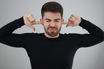 young man with fingers in ears agonized with loud noise - deaf