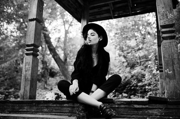 Sensual smoker girl all in black, red lips and hat. Goth dramatic woman smoking thin cigarette....