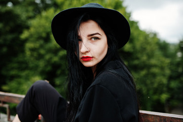 Sensual girl all in black, red lips and hat. Goth dramatic woman.